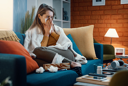 woman on couch blowing nose