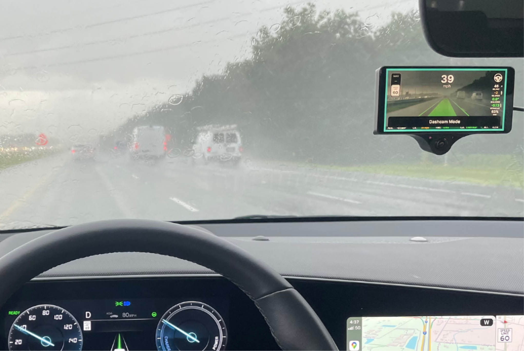 A stormy road, from the perspective of a driver, showing dashboard technology