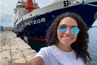 student in front of research vessel