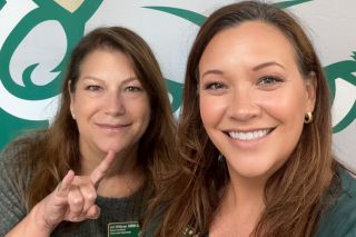 two women holding up "go bulls" hand signals