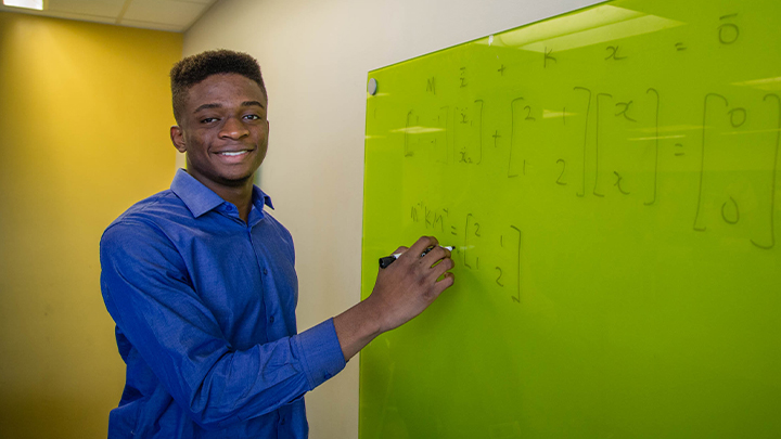 student Temiloluwa working at a white board