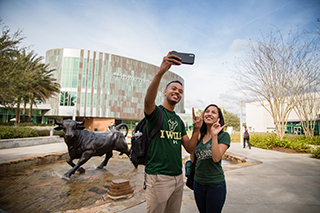 Two students taking a selfie in front of the USF Marshall Student Center on the Tampa, Florida campus.