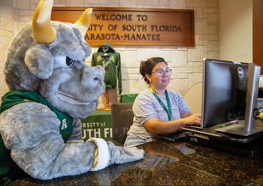 Rocky the Bull and a student look at a computer