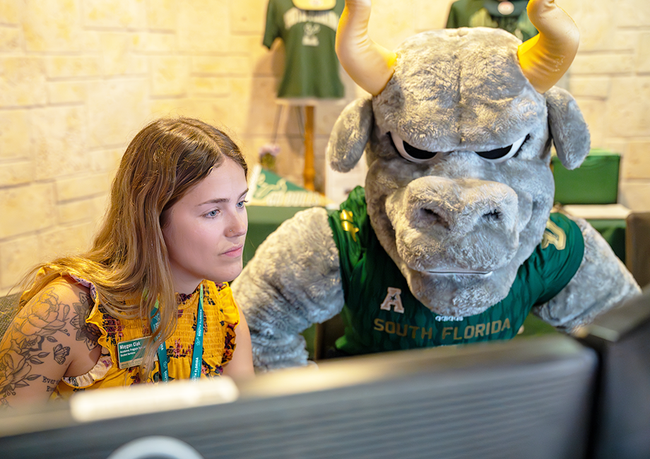 Rocky the Bull and a student looking at a computer screen