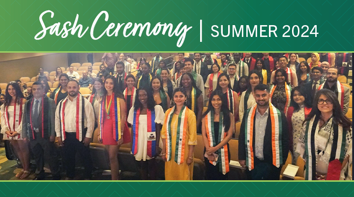 a group of international graduating students with their international sashes on in an auditorium