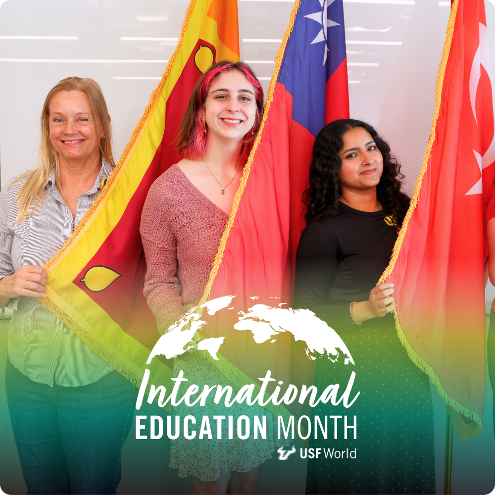 Three people smiling and standing next to international flags