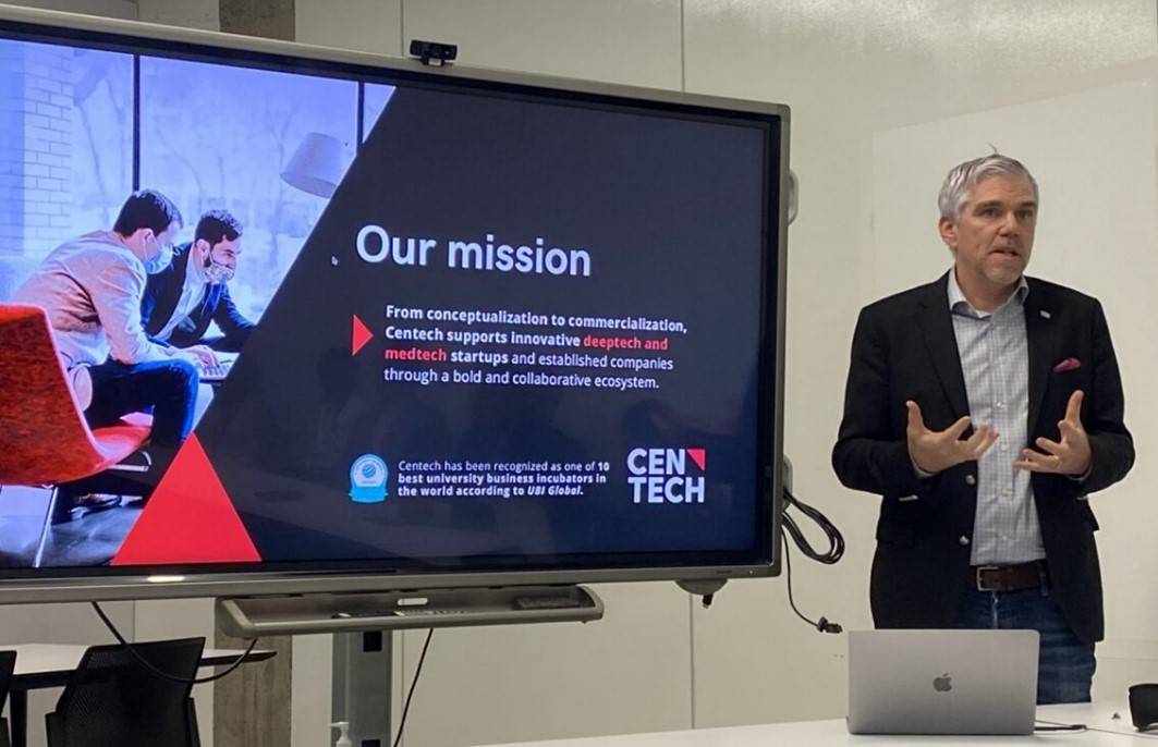 middle-aged caucasian gentleman dressed in jeans and a sports coat presenting in front of an interactive monitor