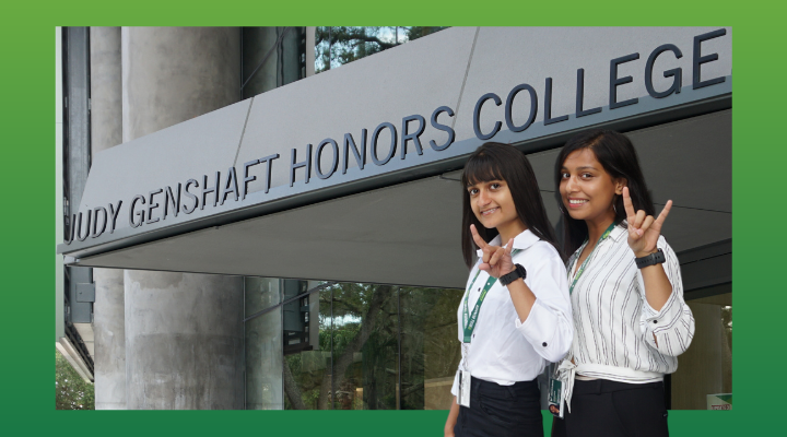 two Indian females dressed in black pants and white shirts stand outside the front of the Honors College building at USF