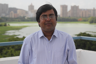 middle-aged India scholar smiles at the camera