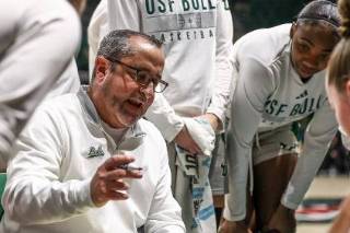 USF women's basketball coach, Jose Fernandez huddles with his players to discuss strategy during a game