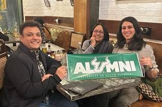 Journalist and USF alumnus Himanshu Nitnaware, Aruna Dasgupta, and Vanessa Martinez proudly display a USF alumni banner