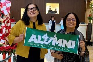 Senior Data Analyst and USF Alumna Nidhi Parasher and Aruna Dasgupta proudly display a USF alumni banner