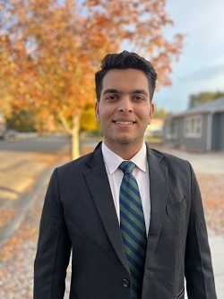 headshot of Mr. Naman Sehgal, USF Students of India Association President; Indian male in a dark suit standing in front of an autumnal maple tree