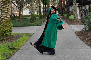 female Indian doctoral student in full regalia celbrating her graduation for the camera