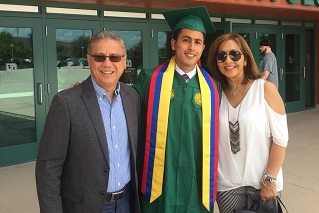 graduation picture of Julian Escallon in his green USF regalia standing between his parents
