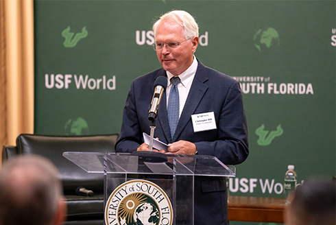 Ambassaor Christopher Hill speaking at the podium with USF logo