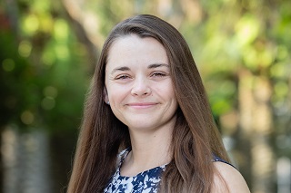 headshot of a young caucasian woman with straight brown har dressed in a blue and white dress