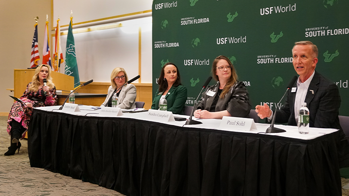 A panel discussion with four people and a moderator sitting down