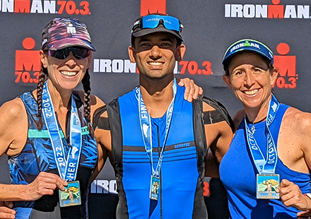 Sharma with two other older women in front of the "Ironman" backdrop