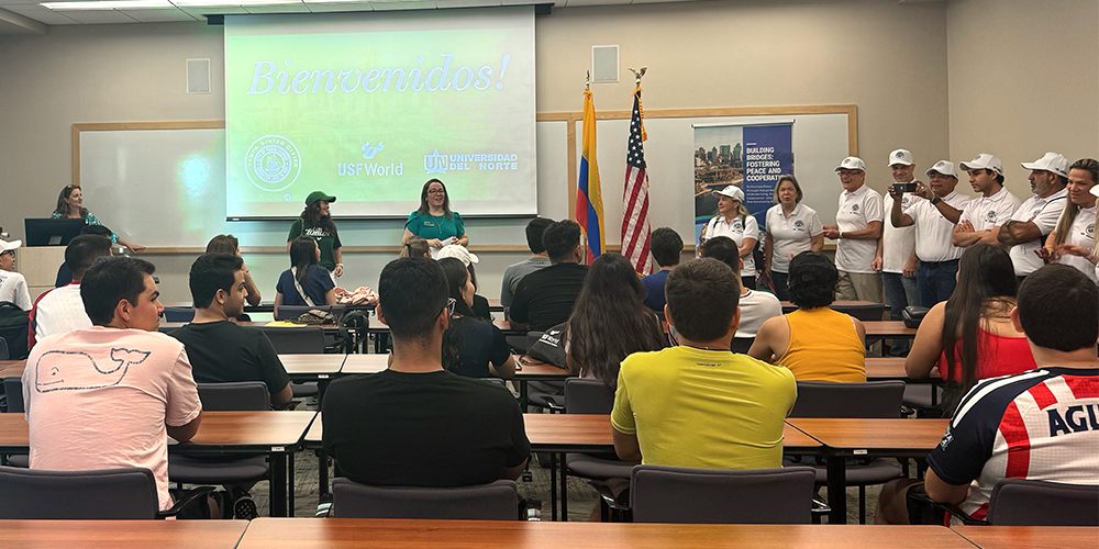 A group of students facing a speaker at the front of the classroom