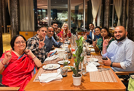 alumni from india sitting at dinner table and smiling at camera