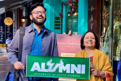 Entrepreneur and USF alumnus Ishan Mitra and Aruna Dasgupta proudly display a USF alumni banner