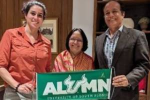 Vanessa Martinez, Aruna Dasgupta, and alumnus entrepreneur Ranvir Singh proudly display a USF alumni banner