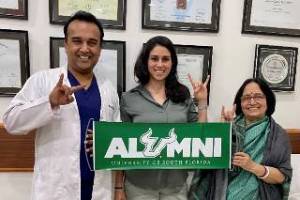 USF alumnus, Co-Medical Director and Chief Cardiologist Dr. Sameer Gupta, Vanessa Martinez, and Aruna Dasgupta proudly displaying a USF alumni banner at MP Heart Clinic in India
