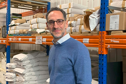 arpesani posing in a warehouse with sacks of ingredients behind him