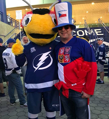 Jakub in a bee mascot costume wearing a lightning symbol of tampa bay rays shirt and standing next to a man wearing Czech Republic hat and shirt