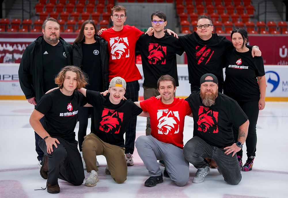 Jakub and a group of people in red and black shirts on a hockey ice rink