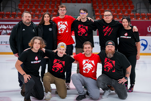 Jakub and a group of people in red and black shirts on a hockey ice rink