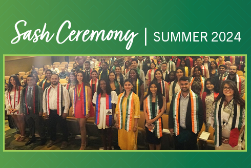 a group of international graduating students with their international sashes on in an auditorium