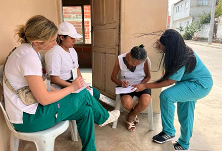 nursing students standing around a colombian woman who is filling out a form