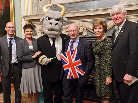 Group of British officials smiling by Rocky the Bull who is holding the British flag