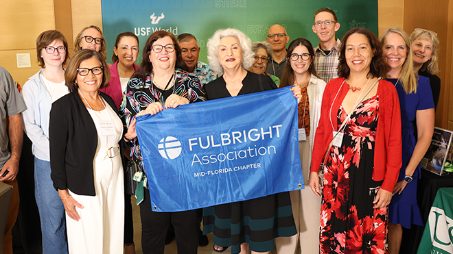 group of people smiling and holding a blue banner that says "Fulbright Association"
