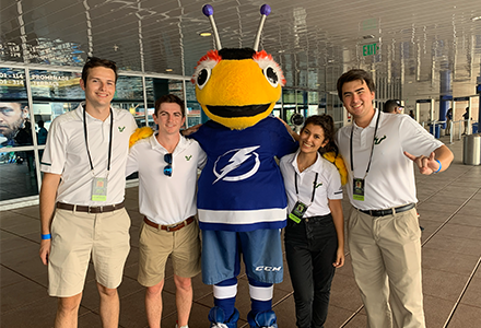 Two people and a mascot bee smiling