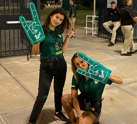 Two students smiling with large foam sports hands