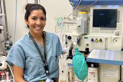 Nurse smiling in front of medical equipment
