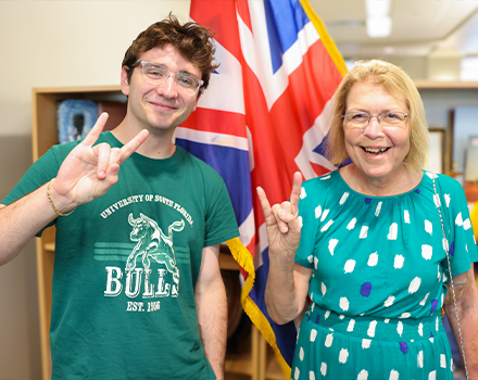 Corinne and Kyle standing together smiling raising the bulls "sign"