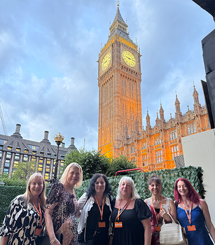 Corinne and a group of people smiling with the an ancient London tower in the background