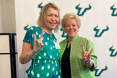 Corinne and USF President Rhea Law standing together smiling raising the bulls