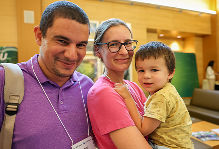 Two people and a child smile at the camera