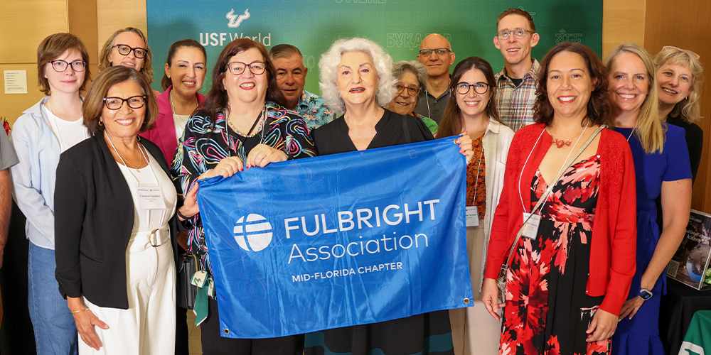 Group of people holding a blue banner with white text that says "Fulbright Association"