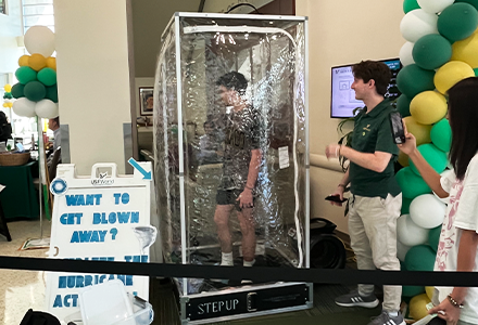 Student standing in a plastic encasing with confetti flying around them