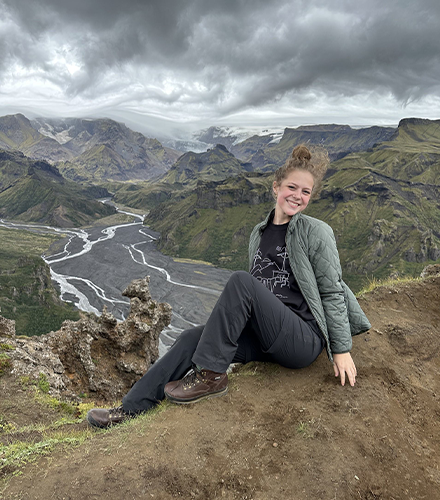 Kelsey smiling with a large mountainous landscape in the background