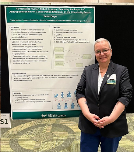 Dogan standing in front of a research presentation board
