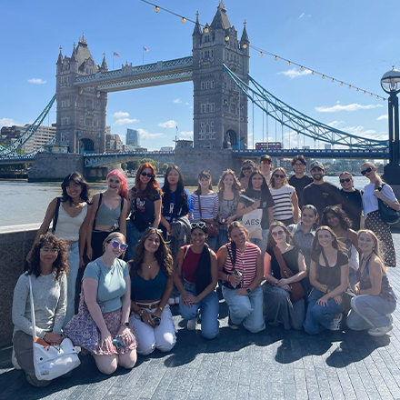 Group of people smiling in front of old bridge