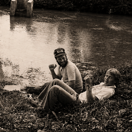 Two people lying in the leaves beside a pond