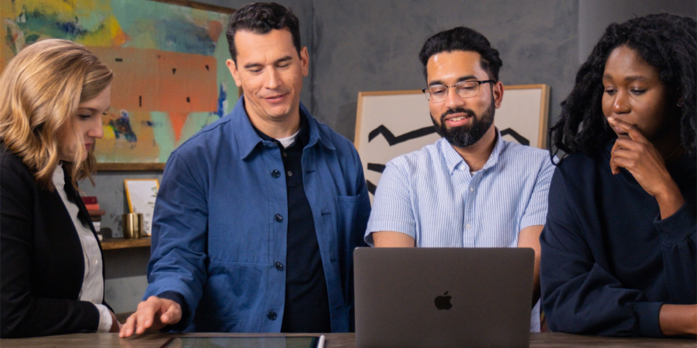 Group of people at table looking at application and smiling